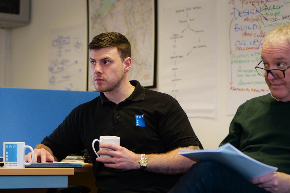 Engineer with a cup of tea at a team meeting